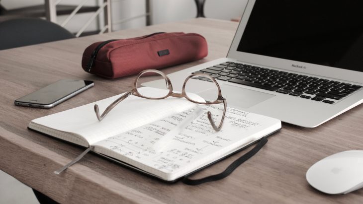 Laptop, notebook, and glasses on a desk